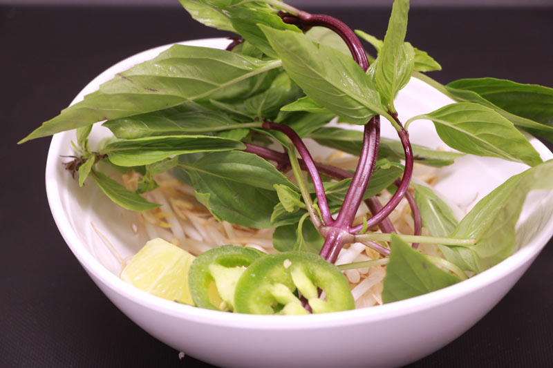 A plate of beansprout, basil, lime and jalapeno